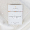 Bracelet on a 'kindness' card with 'Be Kind Humankind' text on a textured surface