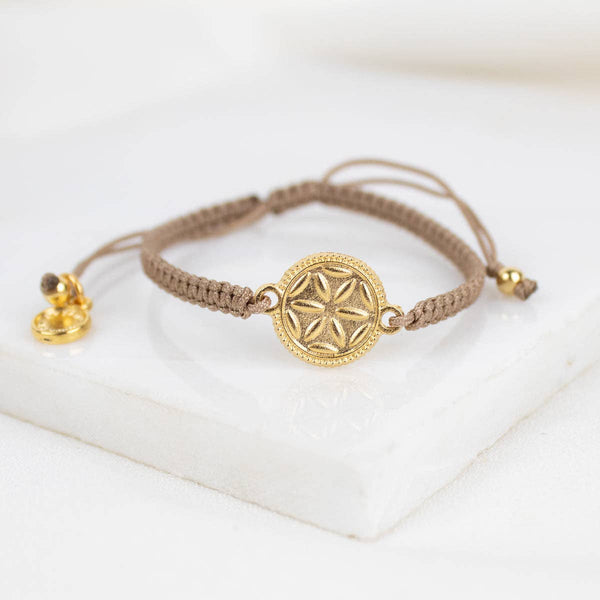 Gold bracelet with a star-shaped clasp on a white surface