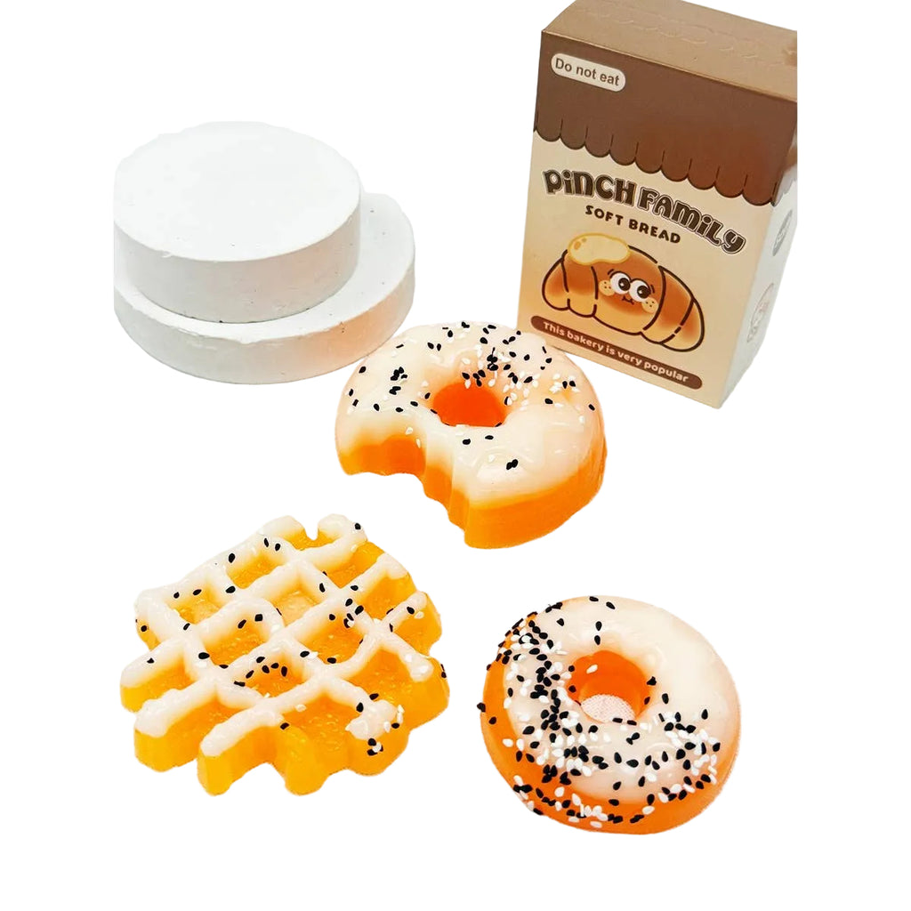 Three bread-shaped cookies with decorative patterns and a box labeled 'Pinch Family Soft Bread' on a white background.