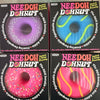 Needoh donut-shaped items arranged in a 2x2 grid on a light surface. Each package shows a different bright donut design: purple with white sprinkles, blue with green swirls, pink with white sprinkles, and pink with yellow swirls.