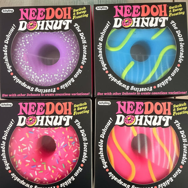 Needoh donut-shaped items arranged in a 2x2 grid on a light surface. Each package shows a different bright donut design: purple with white sprinkles, blue with green swirls, pink with white sprinkles, and pink with yellow swirls.