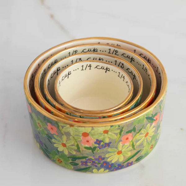 Set of three floral-patterned measuring cups on a white surface