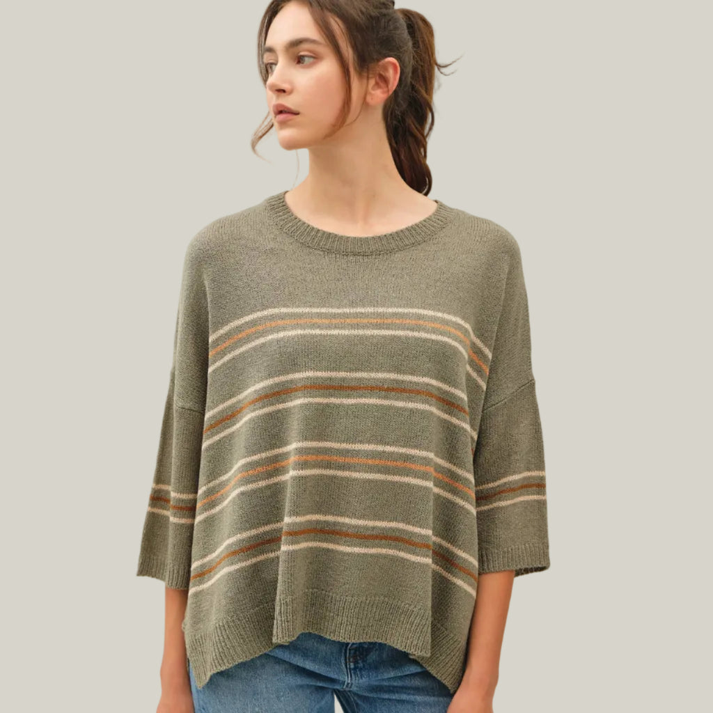 Woman wearing a green striped sweater against a plain background
