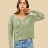 Woman wearing a green ribbed sweater and blue jeans on a white background