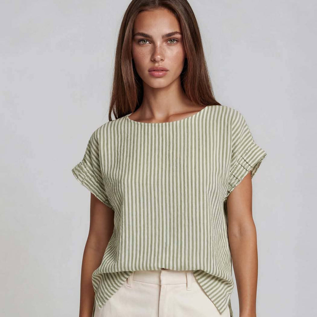 Woman wearing a green and white striped top with ruffled sleeves on a plain background