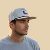 Man wearing a cap with a Texas flag design on a beige background