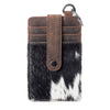 Phone case with cowhide design and brown leather strap on a white background