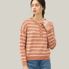 Woman wearing a striped sweater and jeans against a plain background