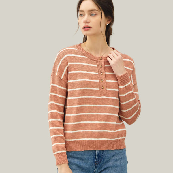 Woman wearing a striped sweater and jeans against a plain background