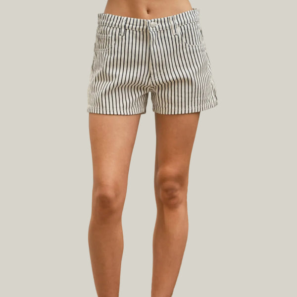 Person wearing striped shorts standing on a wooden deck with a plant in the background