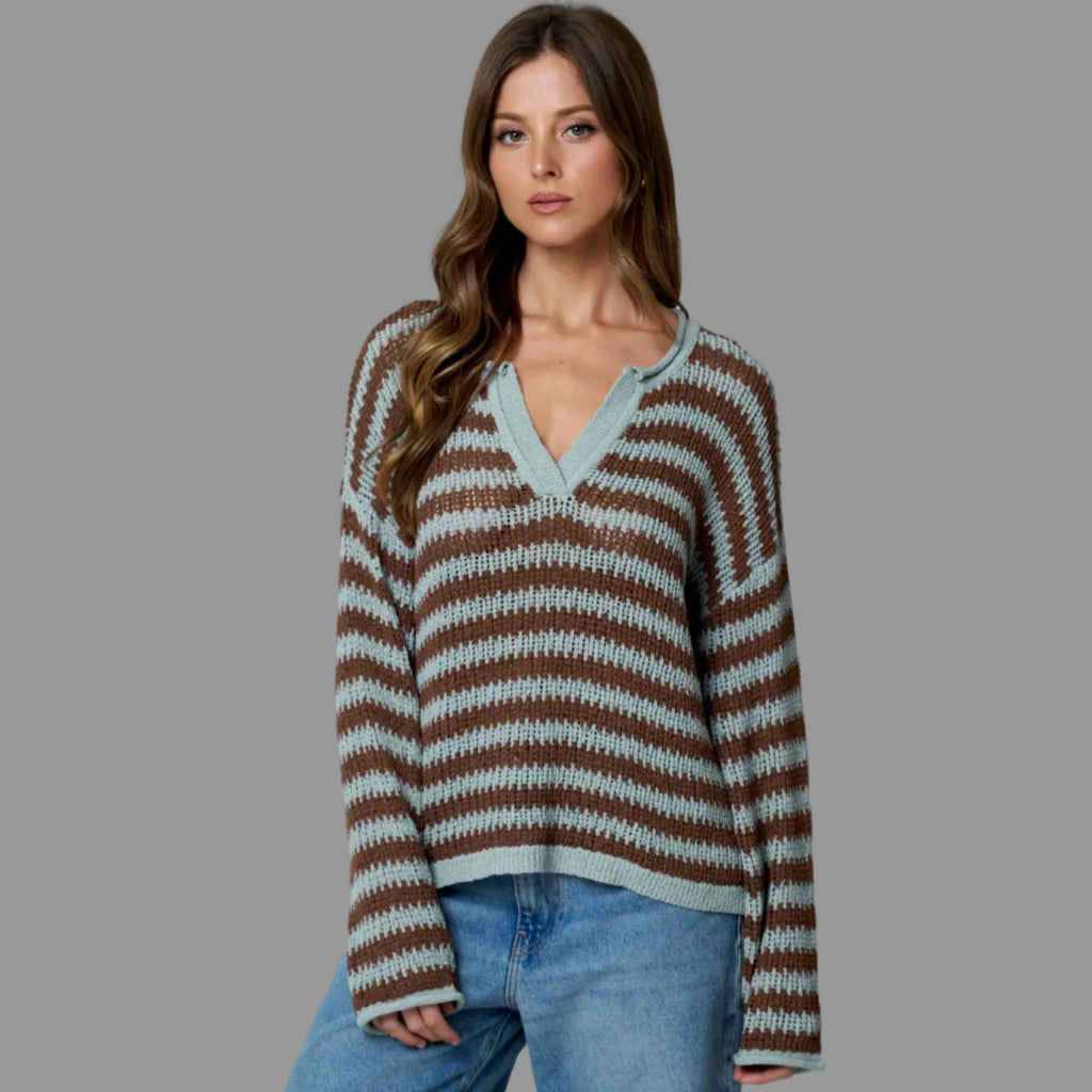 Woman wearing a striped sweater and jeans against a plain background