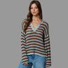 Woman wearing a striped sweater and jeans against a plain background