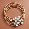 Set of gold necklaces with square pendants on a brown background