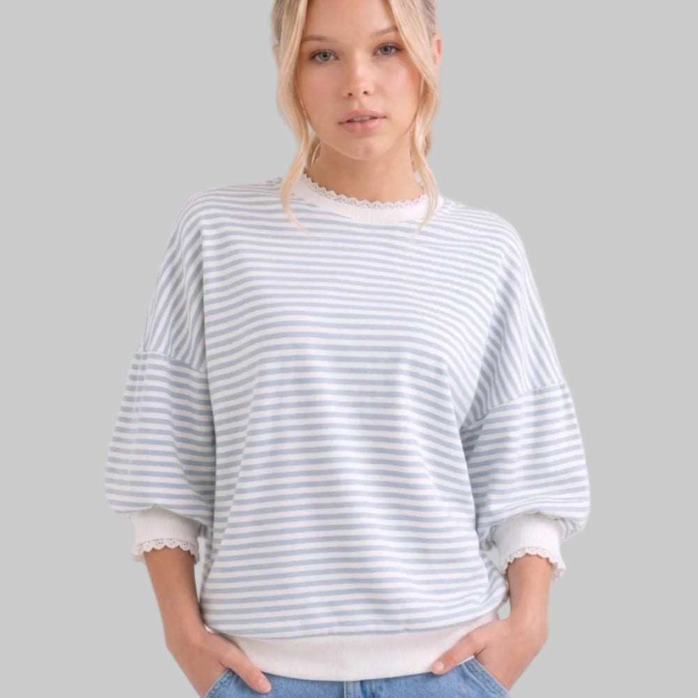 Woman wearing a striped sweater and jeans against a plain background
