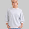 Woman wearing a striped sweater and jeans against a plain background