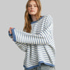 Woman wearing a blue and white striped sweater and jeans on a plain background