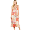 A woman modeling a sleeveless midi dress with a colorful patchwork print of floral and geometric tiles in orange, red, pink, and cream, set against a plain white studio background.