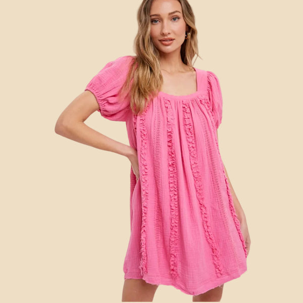 Woman wearing a pink dress with puff sleeves on a white background