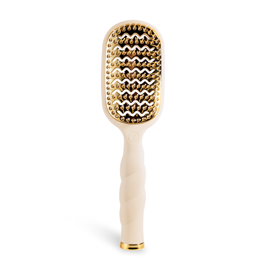 Hairbrush with gold bristle head and white handle on a white background