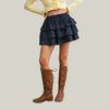 Person wearing a navy ruffled skirt and brown knee-high boots on a plain background
