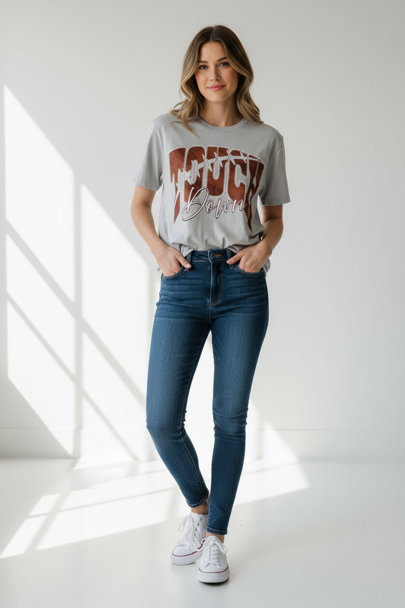 A light gray crewneck sweatshirt featuring a large graphic on the front that reads 'TOUCH Down' in brown and white, laid flat on a speckled granite countertop.