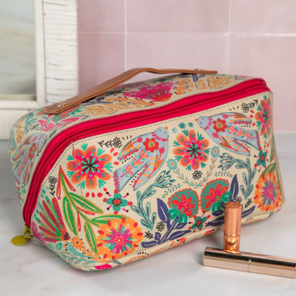 Floral patterned cosmetic bag on a white surface with a pink background
