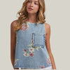 Woman wearing a denim top with floral patterns on a plain background