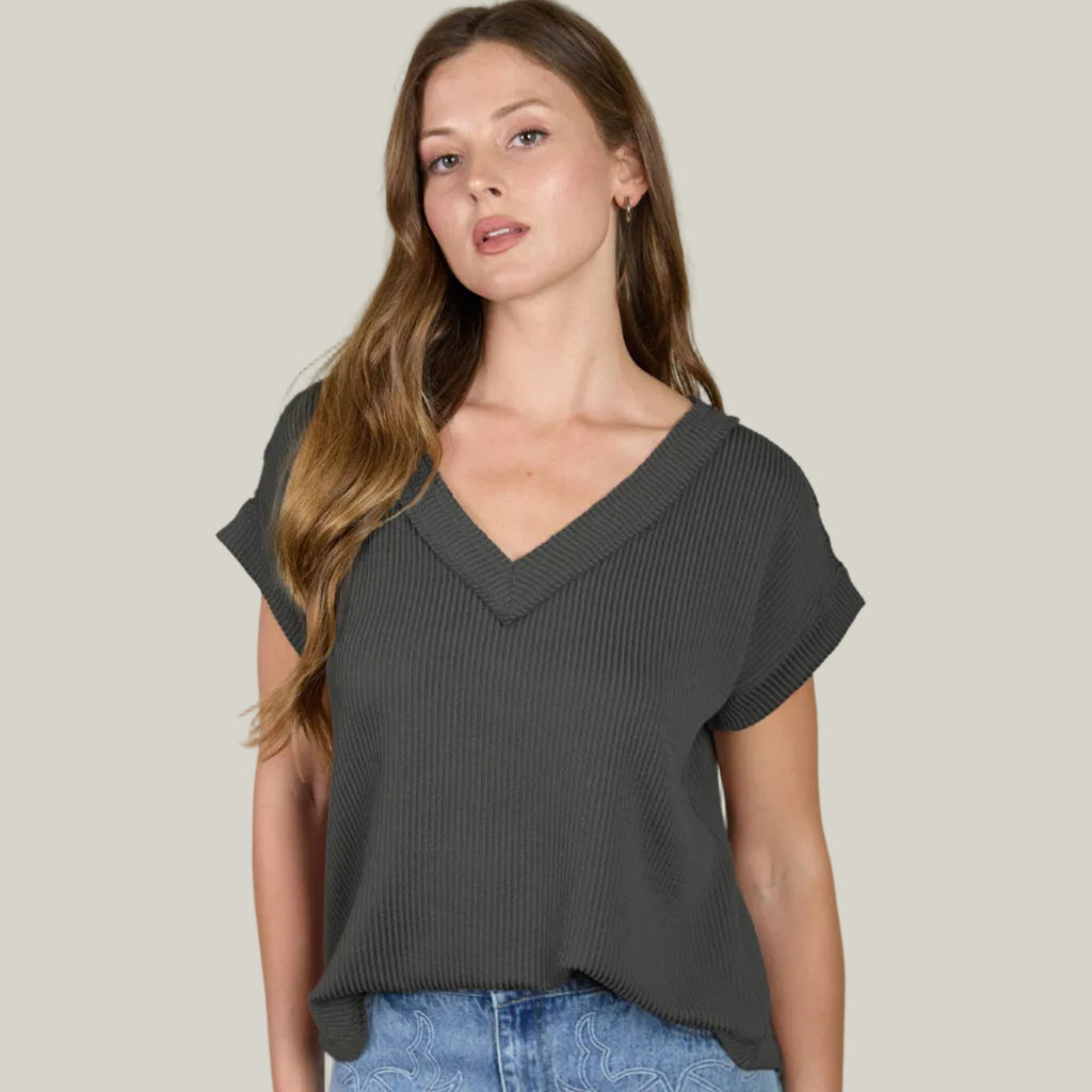 Woman wearing a dark gray top and blue denim skirt on a plain background