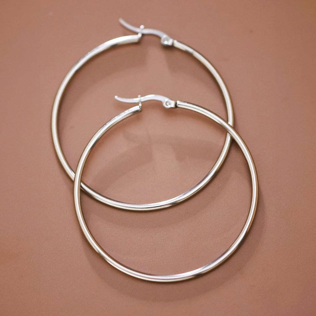 Pair of silver hoop earrings on a brown background