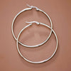 Pair of silver hoop earrings on a brown background