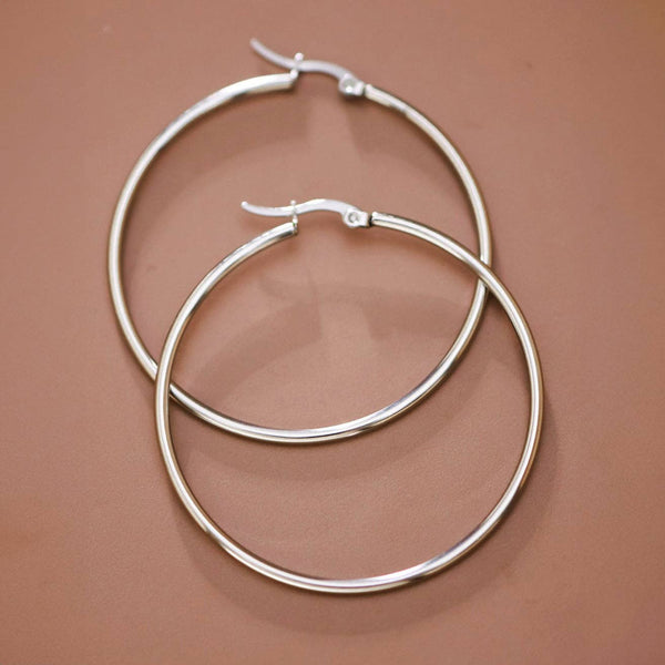 Pair of silver hoop earrings on a brown background