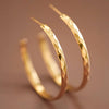 Gold hoop earrings on a brown background