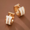 Gold hoop earrings with white bands on a brown background