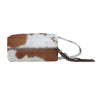 Brown and white cowhide clutch bag with a strap on a white background