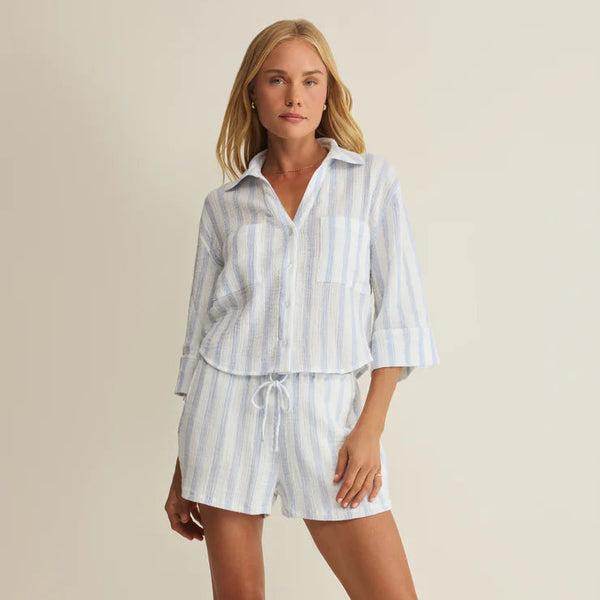 Woman wearing a striped shirt and shorts set on a beige background