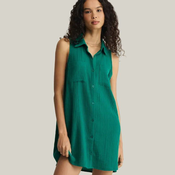 Woman wearing a green sleeveless dress against a beige background