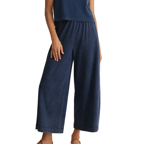 Person wearing navy blue pants and top on a beige background