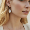 Close-up of a woman wearing a gold necklace and earrings with a blurred background