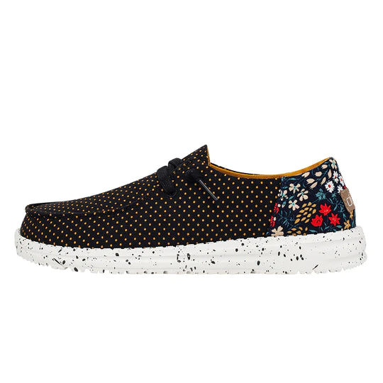 Sneaker with black polka dot pattern and floral side panel on a white background