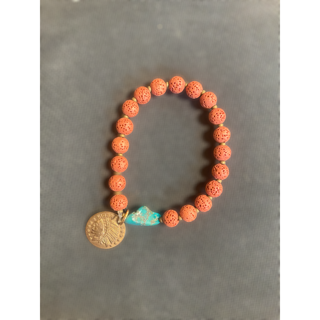 Bracelet with coral beads and a gold and turquoise charm on a gray background