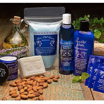 Collection of 'Two Old Goats' skincare products on a wooden surface with almonds and lavender.