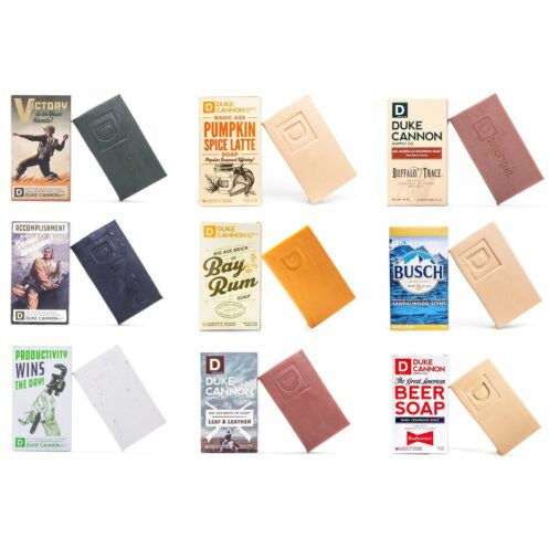 This image displays a collection of Duke Cannon soaps, each packaged in uniquely designed wraps that reflect their specific scents and themes. The soaps come in a substantial 10 oz.